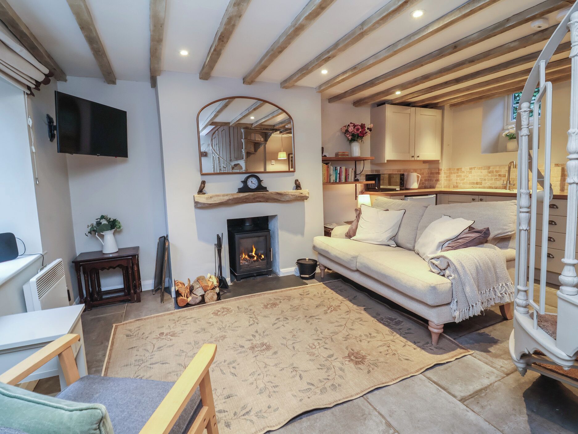 A cozy living room with a fireplace, a sofa, a TV, and a kitchen area in the background.