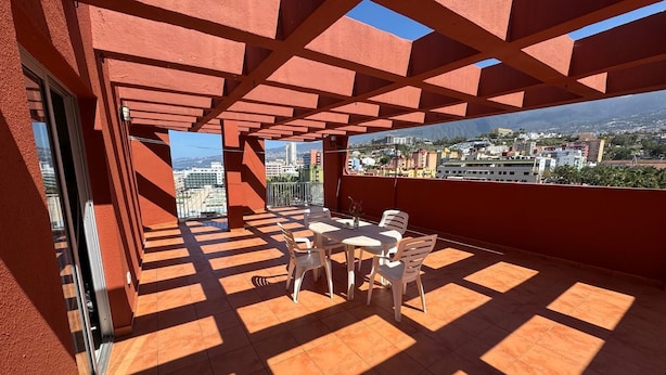 A rooftop terrace with a tiled floor, a table with chairs, and a view of the cityscape. - Penthouse downtown Puerto de la Cruz (Puerto de la Cruz)