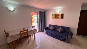 A living room with a sofa, a dining table with chairs, and a sliding glass door leading to an outdoor area. - Penthouse downtown Puerto de la Cruz (Puerto de la Cruz)