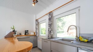 Een moderne keuken met een houten aanrecht, een inbouwfornuis, een spoelbak en een raam met patroon gordijnen.