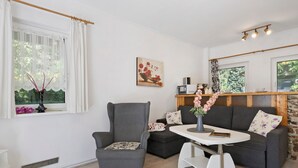 A modern living room with a grey armchair, a sofa, a small white table, and a painting on the wall.