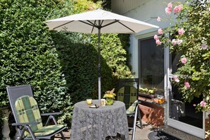 Een terras met een tafel, stoelen en een parasol.