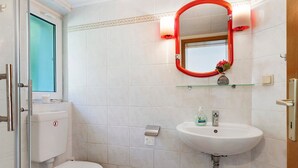 Une salle de bain avec des toilettes, un lavabo et un miroir.