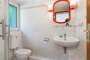 Een badkamer met toilet, wastafel en spiegel.