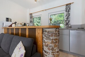 Une cuisine compacte avec une colonne en pierre, un comptoir en bois et une vue sur la verdure à l’extérieur.