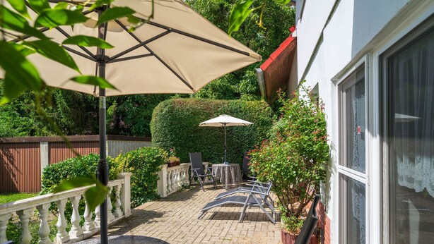 Een terras met een tafel, stoelen en een grote parasol.
