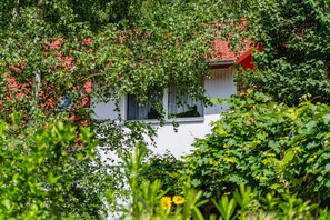 Un edificio blanco de techo rojo, parcialmente oculto por una vegetación verde exuberante.