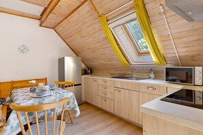 Une cuisine de taille réduite, avec des meubles en bois, un four à micro-ondes et une petite fenêtre ornée de rideaux jaunes.