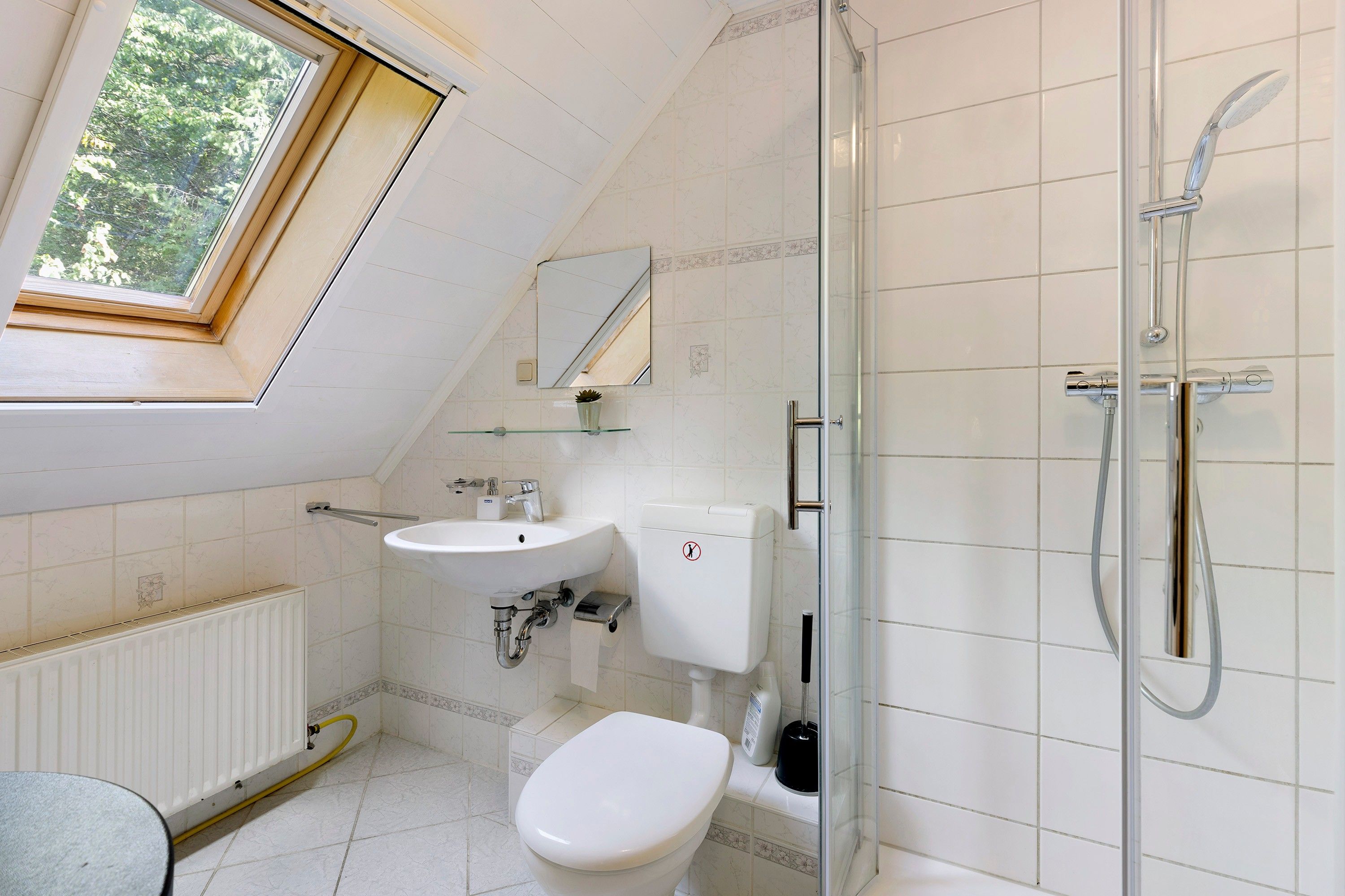 Ein modernes Badezimmer mit Oberlicht, Dusche, Toilette und Waschbecken.