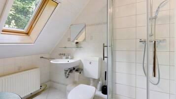 Ein modernes Badezimmer mit Oberlicht, Dusche, Toilette und Waschbecken.