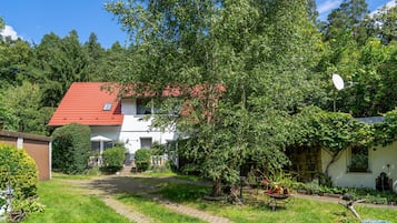 Ein Haus mit rotem Dach, umgeben von üppigem Grün und einem gepflasterten Weg.