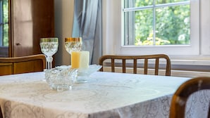 A dining table with a patterned tablecloth, two crystal glasses, a candle, and a glass bowl.