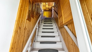 A wooden interior with a staircase leading to a bright room.