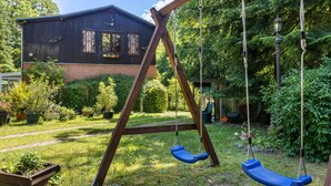 A wooden swing set in a backyard with a house in the background.