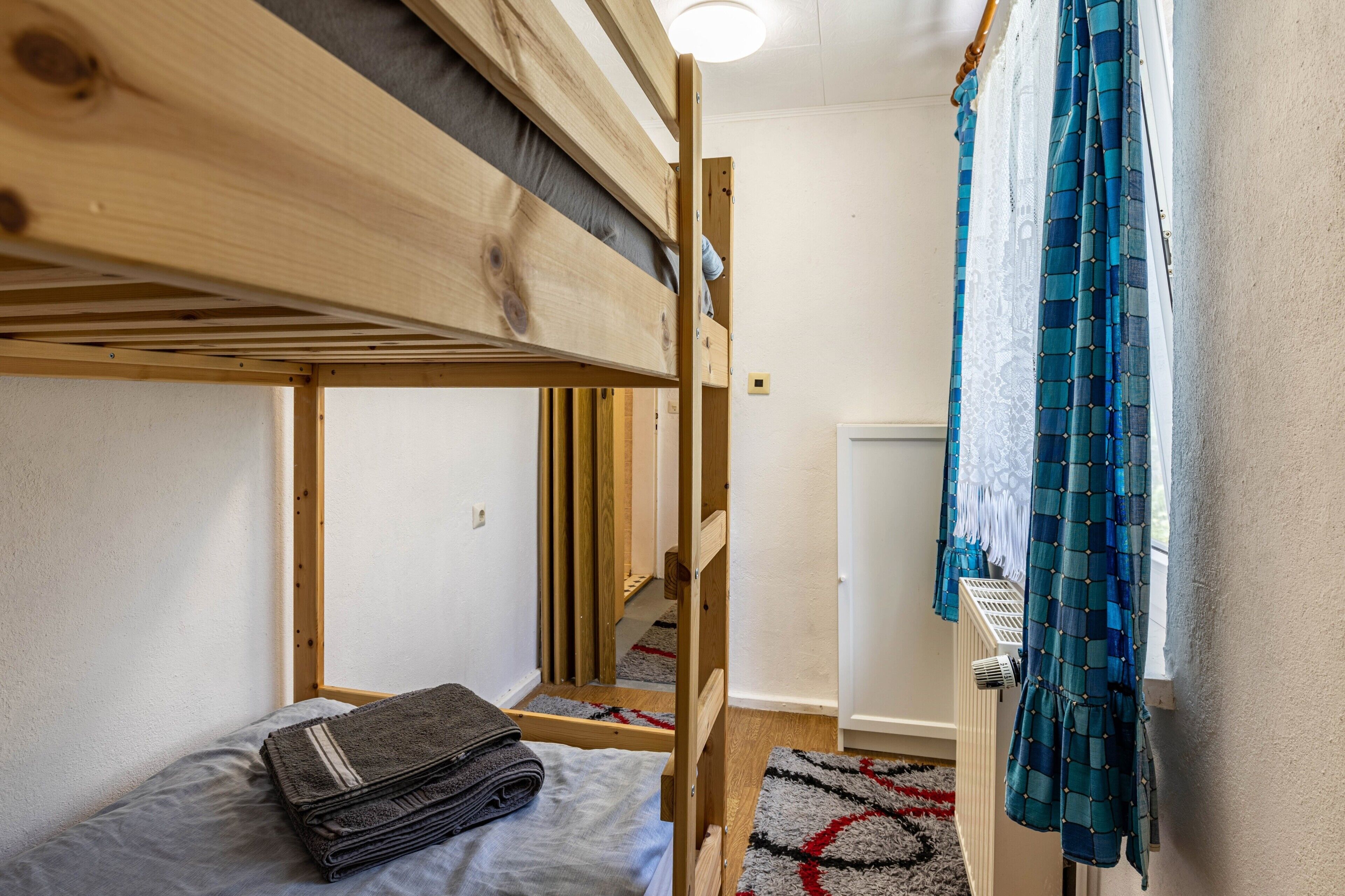 Una cama litera con un colchón gris, una manta gris doblada y un cabecero de madera.