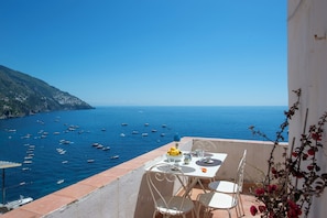 A terrace with a table set for two, overlooking a coastal area with boats. - Rosa sul Mare Positano - Panoramic Sea View (Positano)