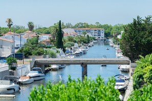 A canal with boats docked on both sides, a bridge crossing over the water, and buildings with red-tiled roofs in the background. - WELCS APARTMENT 277 EMP with canal view (Empuriabrava)