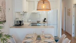 En matplats med ett bord dukat för fyra personer, en hängande lampa och ett kök i bakgrunden.