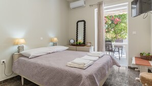 A bedroom with a bed, bedside lamps, a mirror, a TV, and a view of the outdoors. - Apartment 'Astros' with Balcony (Paralio Astros)