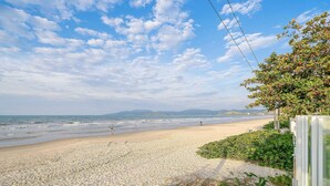 Ein Strand mit blauem Himmel, sandigem Ufer und Blick aufs Meer.