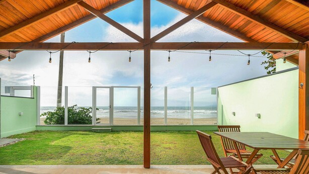 Eine überdachte Terrasse mit Blick auf den Strand, Holzmöbel und Lichterketten.