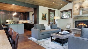 A spacious living area with a fireplace, a kitchen with dark wooden cabinets, and a dining area with a table and chairs. - Basingdale Hollow - For 10 (Vail)