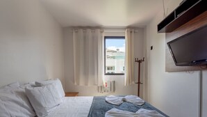 A hotel room with a bed, a window with curtains, a coat rack, a television, and a radiator. - Apt w Barbecue 350m fr Canasvieiras Beach Aal0204 (Florianópolis)