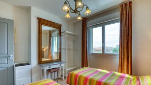 Un dormitorio con dos camas, un escritorio, un espejo, un calentador y una ventana con cortinas.