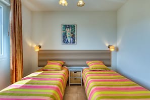 Una habitación con dos camas, cabeceros, un cuadro y dos lámparas de pared.
