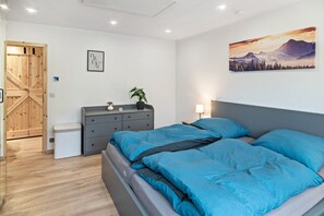 Une chambre à coucher avec un lit, une commode et un tableau accroché au mur.