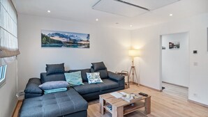 Una sala de estar moderna con un sofá modular, una mesa de centro de madera y un cuadro en la pared.