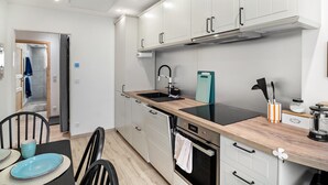 Una cocina moderna con armarios blancos, encimera negra, un lavabo y una estufa.