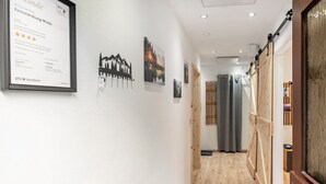 Un pasillo con diplomas enmarcados en la pared, piso de madera y una puerta corrediza con cortina.