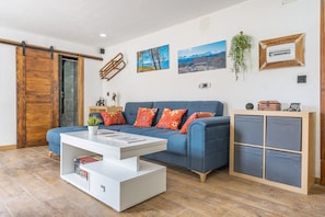 Una sala de estar moderna con un sofá azul, una mesa de centro blanca y un mueble de madera.