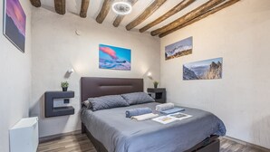 A bedroom with a bed, bedside tables, wall-mounted artwork, and a built-in bench.