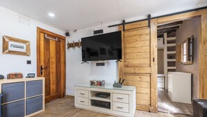 A room with a TV, wooden sliding door, a glass cabinet, and a small kitchenette.