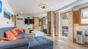 A modern living room with a sectional sofa, a flat-screen TV, and a dining area.