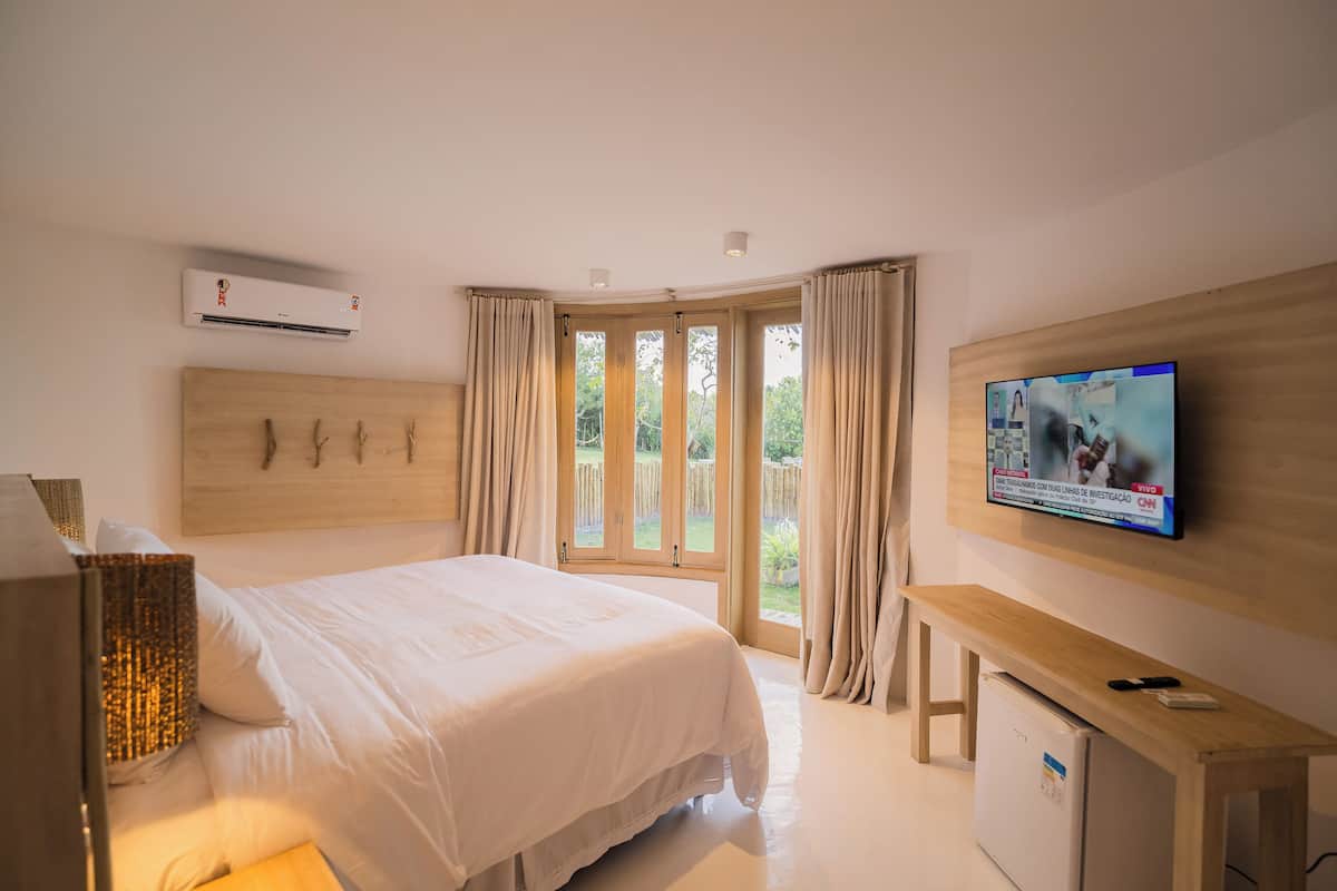 Une chambre à coucher avec un lit, une télévision, un bureau et une fenêtre avec des rideaux.