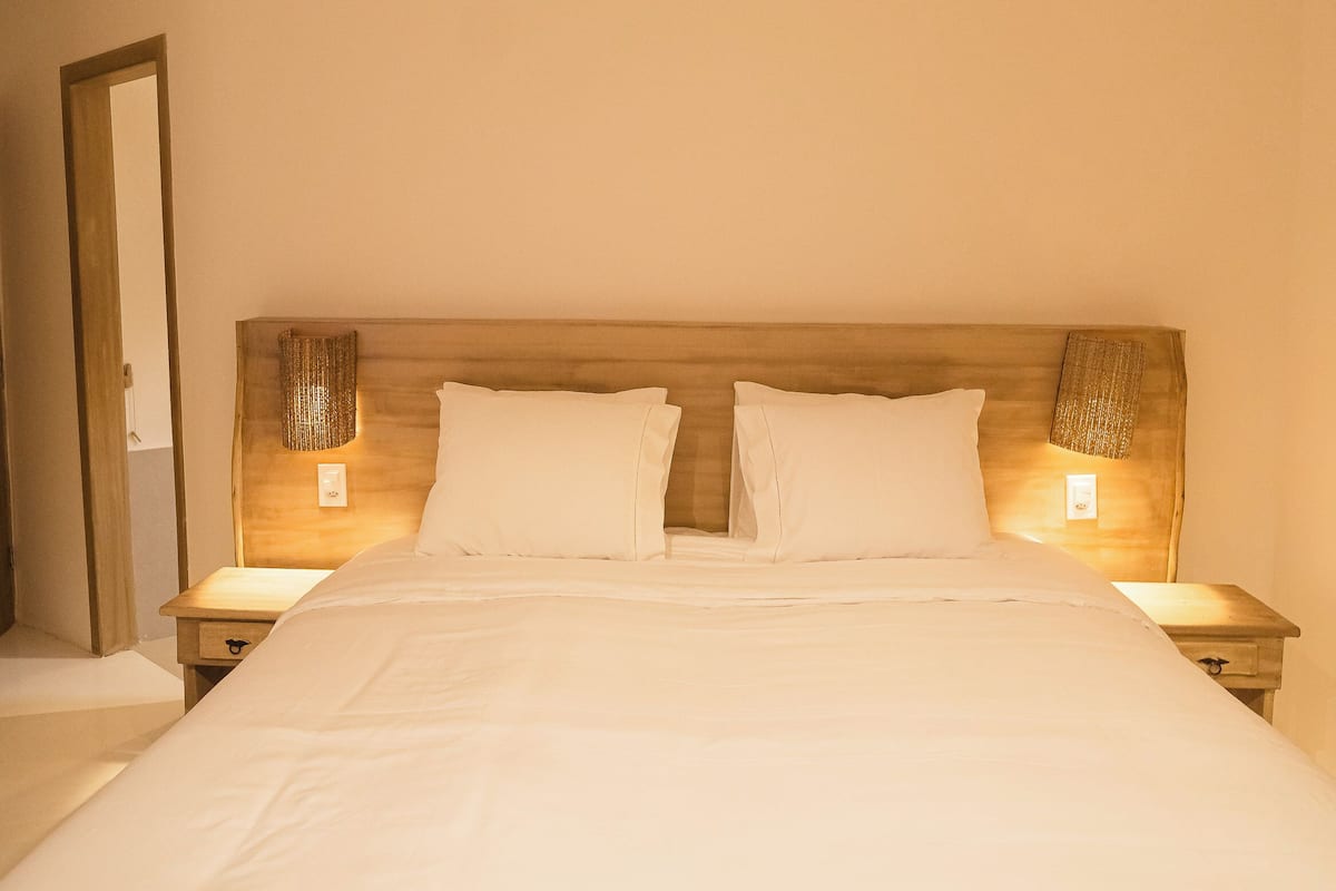 Un lit bien fait, avec du linge de lit blanc et deux lampes de chevet.