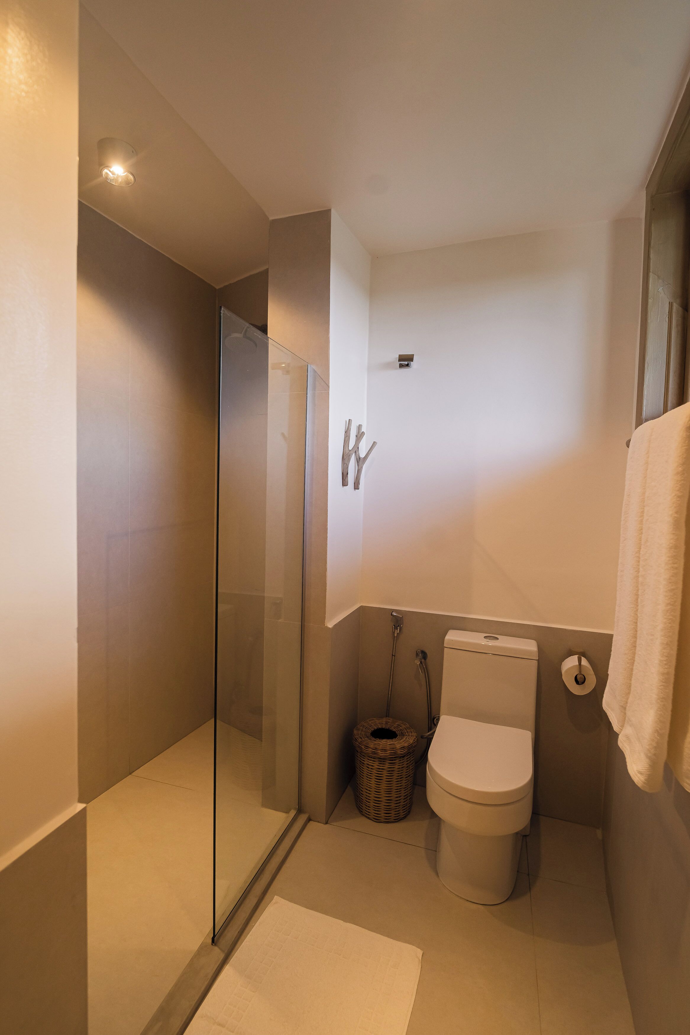 Ein modernes Badezimmer mit Duschkabine aus Glas, Toilette und Korbwannenaufsatz.
