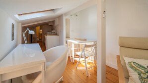 A modern, well-lit room with a white desk, a white chair, a bathtub, and a sofa. - Bairro Alto Tiny Studio by Homing (Lisbon)