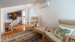 A modern living room with a sofa, two armchairs, a desk, and a patterned rug. - Bairro Alto Tiny Studio by Homing (Lisbon)