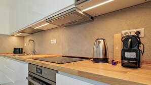 Una cocina moderna con horno empotrado, cafetera y hervidor sobre la encimera.