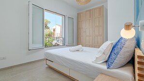 Un dormitorio con cama, ventana, armario y una lámpara colgante.