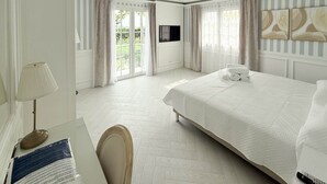 Habitación de hotel con cama, escritorio con lámpara, televisor y vista al exterior.