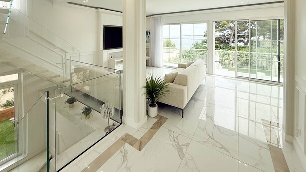 Amplia sala de estar con diseño moderno, que incluye una escalera de cristal, un ventanal con vistas al exterior y una zona de estar cómoda.