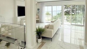 Una sala de estar moderna con un sofá, una mesa de centro de vidrio y una planta en maceta.