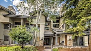 A multi-story residential building with a covered front porch, stone accents, and a landscaped garden with a pathway leading to the entrance. - Ridgepoint Retreat Mountain Escape for 8 w/ Resort Amenities (Avon)