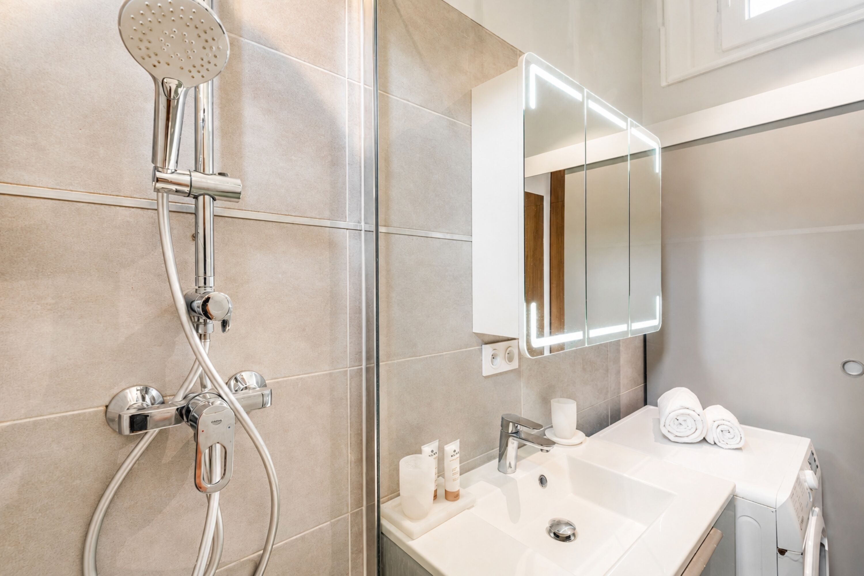 A modern bathroom with a shower, sink, and mirror.