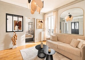 A modern living room with a sofa, a coffee table, and artwork on the walls. - 1536 Daumesnil (Paris)